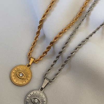 Dois colares com pendentes redondos dourado e prateado sobre tecido branco