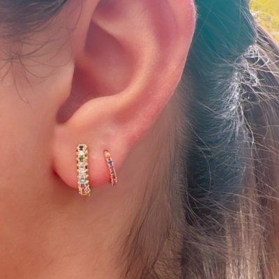 Orelha com dois brincos de argola dourados com pedras coloridas