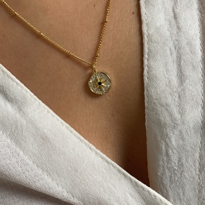 Colar dourado com pendente redondo de pedras e camisa branca