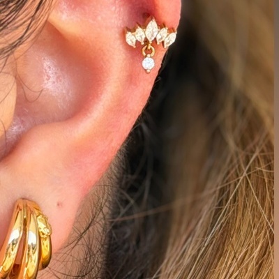 Piercing e brincos dourados com pedras em orelha