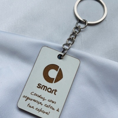 Porta-chaves branco retangular com texto e logotipo castanhos sobre tecido branco