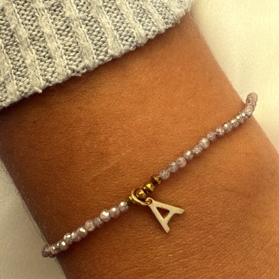 Pulseira com contas cinzentas e pendente letra A no pulso