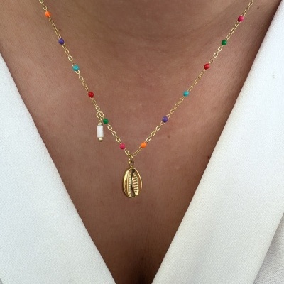 Colar dourado com contas coloridas e pingente de concha sobre roupa branca