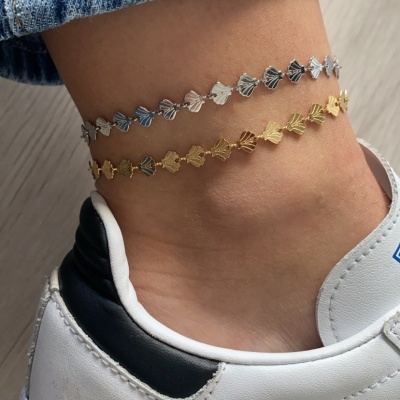 Tornozeleiras dourada e prateada em tornozelo com sapato branco e azul