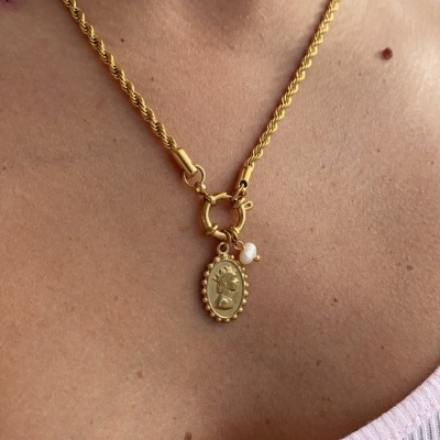 Colar dourado com pendente oval e pérola, usado com camisola cor-de-rosa claro