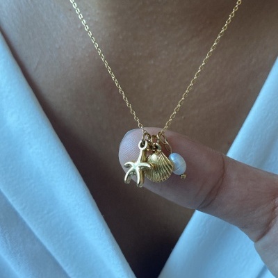 Colar dourado com pendentes de estrela-do-mar, concha e pérola