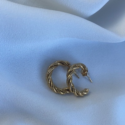 Brincos de argola dourados torcidos sobre tecido branco