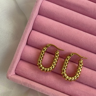 Brincos de argola dourados em caixa rosa de veludo com fundo branco