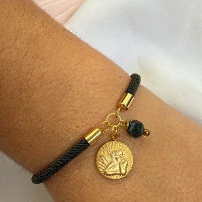 Pulseira preta com pendentes dourados e conta preta no pulso