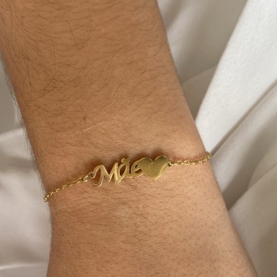 Pulseira dourada com texto 'Mãe' e coração
