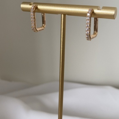 brincos dourados com pedras brilhantes num suporte metalico dourado