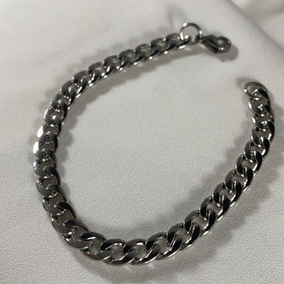 Pulseira de corrente grossa prateada sobre tecido branco