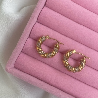 Brincos de argola dourados com pedras exibidos em estojo rosa acolchoado