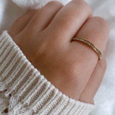 Mão com anel dourado com pedras e malha branca