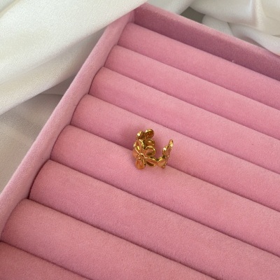 Anel dourado com design de folhas numa caixa rosa para anéis