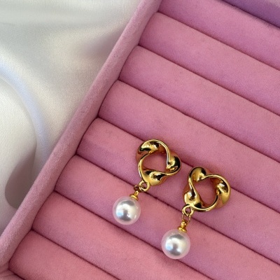 Brincos dourados com pedra branca num estojo rosa em tecido aveludado