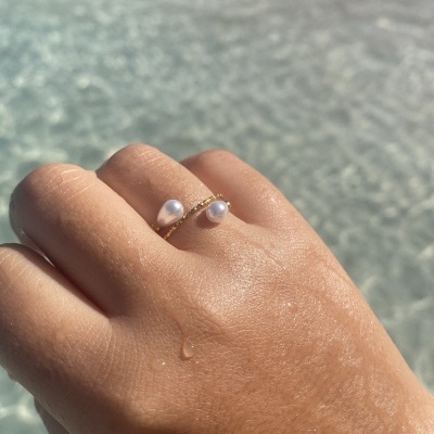 Anel dourado com pérolas em mão sobre água clara