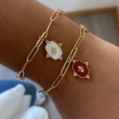 Pulseiras douradas com pendentes em esmalte branco e vermelho no pulso