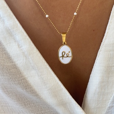 Colar dourado com pérolas e pendente oval branco com inscrição 'fé'