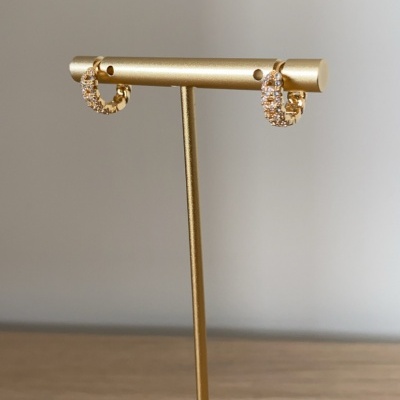 Brincos de argola dourados com pedras brilhantes num suporte dourado