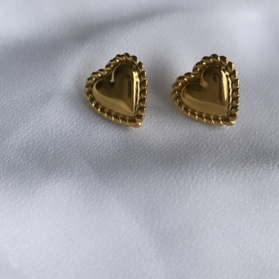 Brincos coração dourados com borda texturizada sobre tecido branco