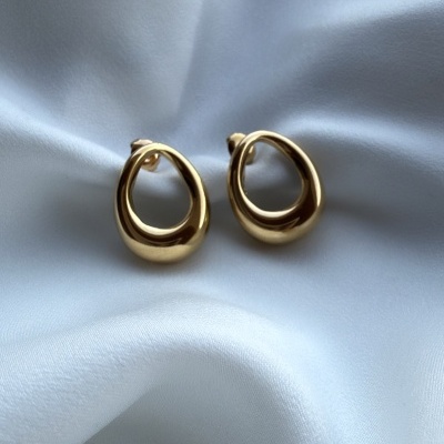 Brincos dourados ovais sobre tecido branco