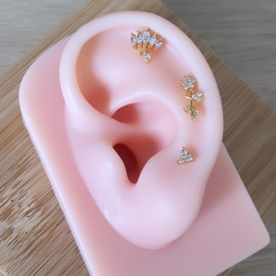 Modelo em silicone rosa de orelha com brincos dourados e pedras brilhantes