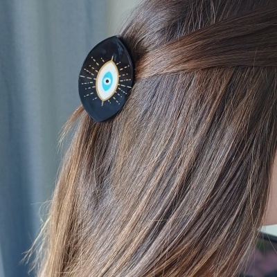 Prendedor de cabelo preto com olho azul decorativo em cabelo castanho claro