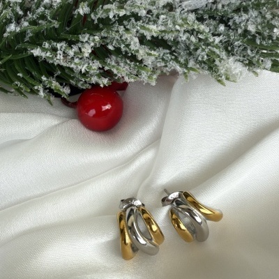 Brincos bicolor dourado e prateado sobre tecido branco com decoração festiva