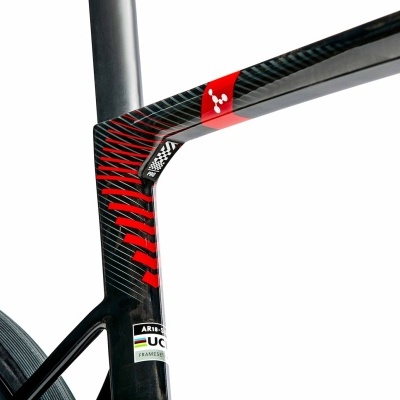 Quadro de bicicleta de carbono preto com padrões vermelhos e etiquetas UCI em fundo branco