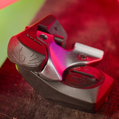 Dispositivo eletrônico preto e cinza com botão CR2032 sobre madeira escura