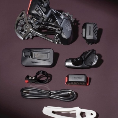 Conjunto componentes bicicleta SRAM preto cinza branco com detalhes vermelhos sobre superfície roxa