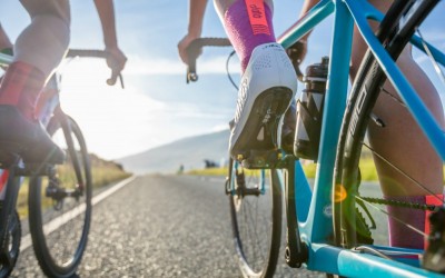 Ciclistas na estrada com bicicletas azul e meias cor-de-rosa DELETE