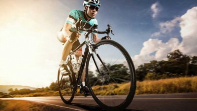 Ciclista de bicicleta de estrada numa estrada ao pôr do sol