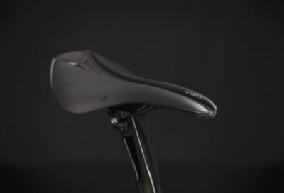 Selim de bicicleta preto montado num canote de carbono, fundo escuro