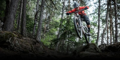 Pessoa em bicicleta de montanha a saltar numa floresta