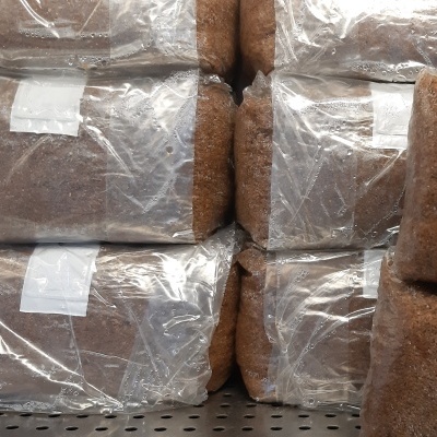 Bolsas transparentes com material castanho empilhadas sobre superfície metálica