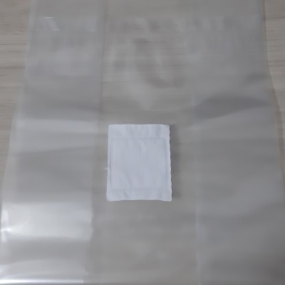 Saco plástico translúcido com etiqueta branca ao centro numa superfície de madeira