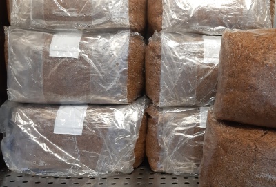 Bolsas transparentes com material castanho empilhadas sobre superfície metálica