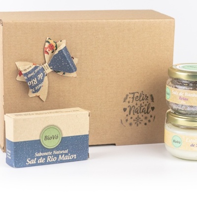 Conjunto de produtos de cuidado corporal BioVó com sabonete, sais de banho e esfoliante, caixa castanha com laço e carimbo Feliz Natal.