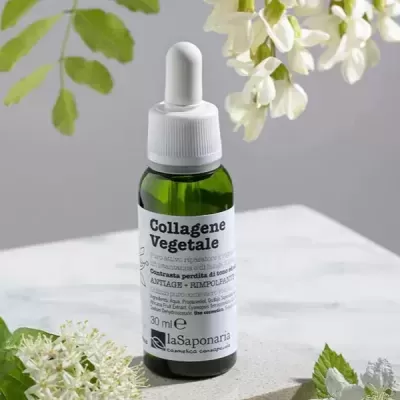 Frasco verde com conta-gotas branco de Collagene Vegetale rodeado por flores brancas