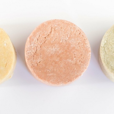 Três pós compactos redondos em tons pastel alinhados