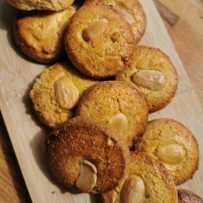 Biscoitos redondos dourados com amêndoas inteiras sobre tábua de madeira