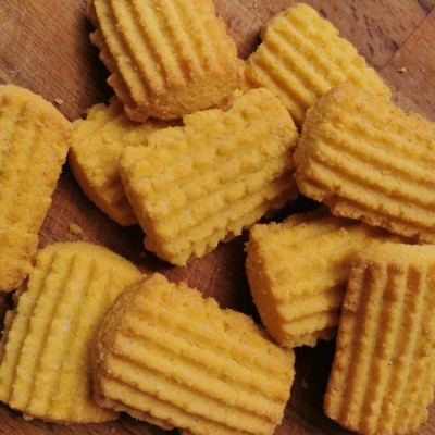 Bolinhos fritos amarelos com textura canelada sobre madeira