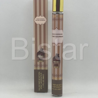 Perfume em frasco de vidro e embalagem de papelão às riscas castanhas e bege com texto CHOC OVERDOSE GIVE ME GOURMAISE.