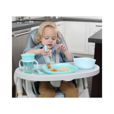 Bebé na cadeira alta a comer com prato e copo azul na bandeja