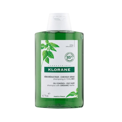 Frasco de champô verde Klorane com rótulo branco e ilustração de planta