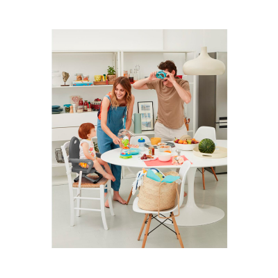 Mesa de jantar branca com cadeiras, brinquedos para criança, fruteira com melancia e família na cozinha