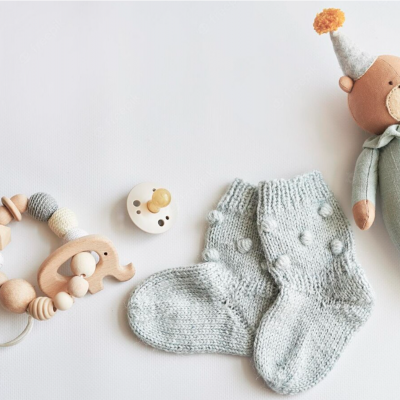 Brinquedo de madeira, chupeta, meias cinzentas e boneco de ursinho em fundo branco