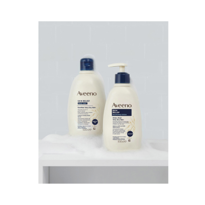 Produtos Aveeno Skin Relief body wash e loção nutritiva em frascos brancos com tampas azuis, sobre espuma branca e fundo azulejado azul claro.